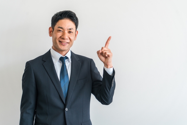 指を立てるスーツの男性